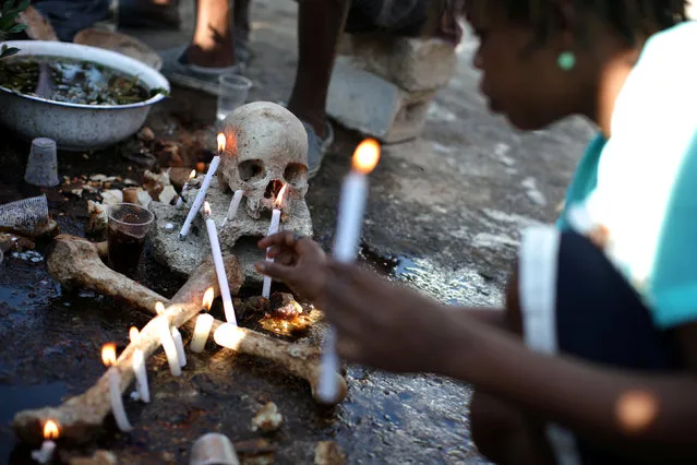 A voodoo believer makes offerings during celebrations at the cemetery of Port-au-Prince, Haiti, November 1, 2017. (Photo by Andres Martinez Casares/Reuters)