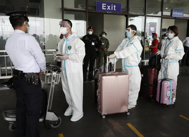 Foreigners wear protective suits as they enter the departure area of Manila's International Airport, Philippines on Friday, May 22, 2020. Some airlines began flights in and out of the country as the capital eases it's lockdown while it continues to fight the spread of the new coronavirus. (Photo by Aaron Favila/AP Photo)