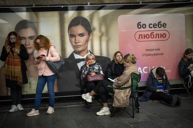 People sit in the Kyiv subway, using it as a bomb shelter, Ukraine, on Wednesday, October 19, 2022. (Photo by Emilio Morenatti/AP Photo)