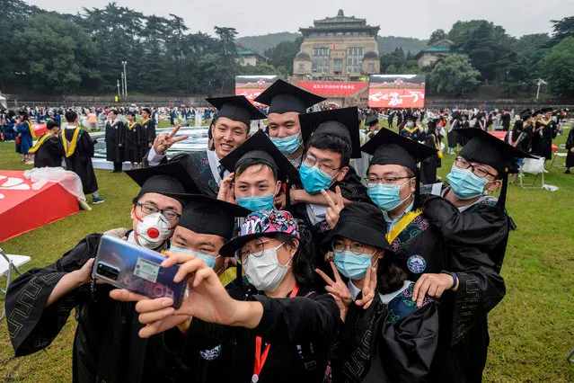 This photo taken on June 20, 2020 shows university graduates wearing face masks taking a selfie during their graduation ceremony at Wuhan University in Wuhan in China's central Hubei province. (Photo by AFP Photo/China Stringer Network)