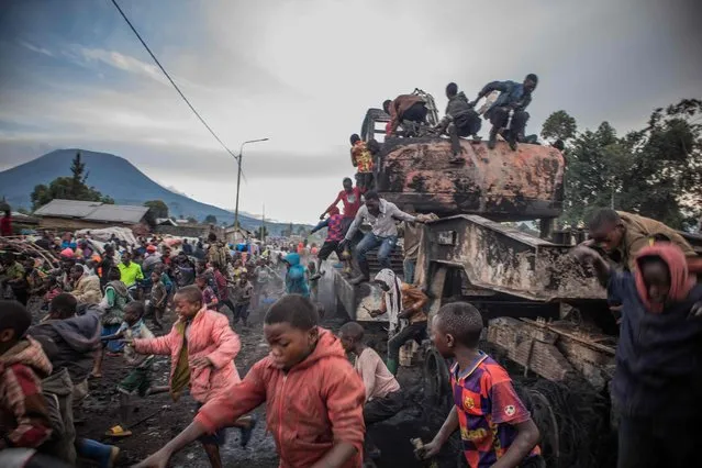 Residents disperse while from a vehicle belonging to the United Nations Organization Stabilization Mission in the Democratic Republic of the Congo (MONUSCO) in Kanyaruchinya, part of Nyiragongo territory in the Democratic Republic of Congo, on November 2, 2022, after it was set on fire overnight by angry residents. (Photo by Aubin Mukoni/AFP Photo)