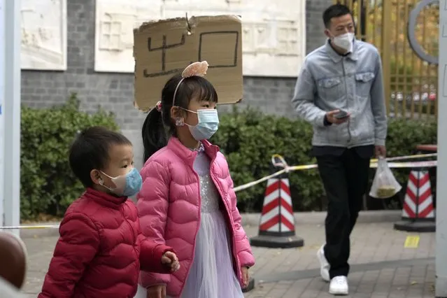 Children wearing masks walk by a sign which reads “Exit” at a COVID test station in Beijing, Sunday, November 6, 2022. (Photo by Ng Han Guan/AP Photo)
