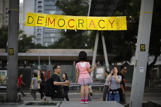 A girl poses next to a sign at an area blocked by pro-democracy protesters outside of the government headquarters building in Hong Kong October 11, 2014. Hundreds of student activists camped overnight at major protest sites in Hong Kong as the democracy movement sought to regather momentum after the government called off talks with its leaders aimed at defusing unrest in the global financial hub. (Photo by Carlos Barria/Reuters)