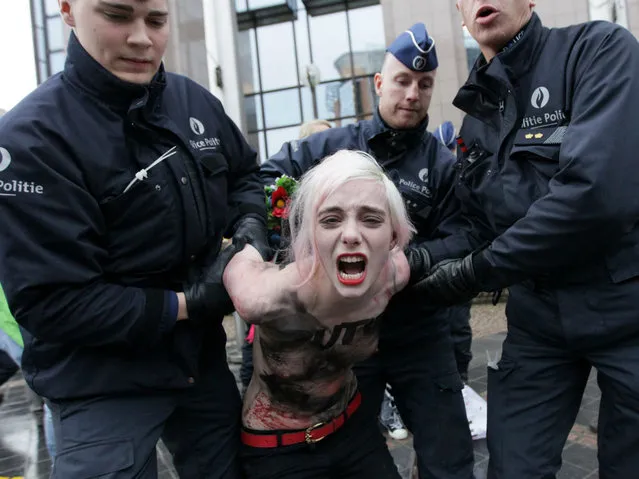 An activist of Ukraine's feminist movement Femen is taken away by the police as she demonstrates by the EU Council building where the EU-Russia summit is taking on December 21, 2012 in Brussels, Belgium. (Photo by Georges Gobet/AFP Photo)