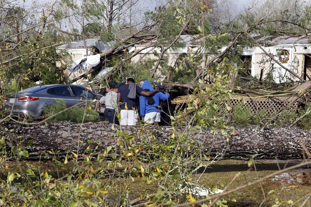 Friends and family pray outside a damaged mobile home, Wednesday, November 30, 2022, in Flatwood, Ala., the day after a severe storm swept through the area. Two people were killed in the Flatwood community just north of the city of Montgomery. (Photo by Butch Dill/AP Photo)