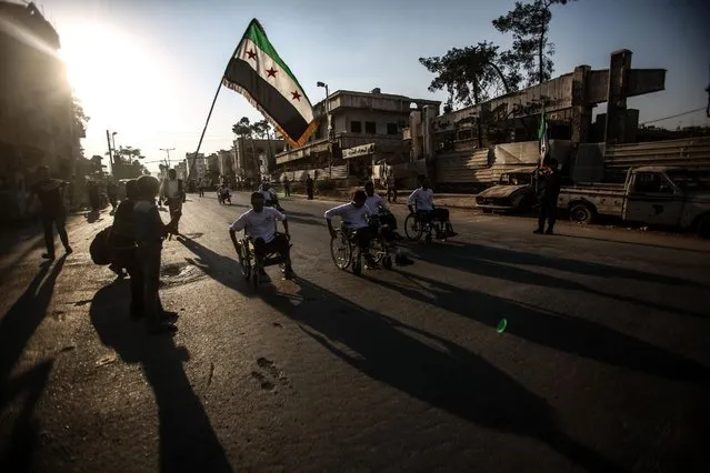 A child waves the Syrian rebels flag as Syrians on wheelchairs participate in a race in Douma, Syria, 08 September 2016. People who suffered disabilities in the Syrian war joined the race held under the slogan “searching for life”. (Photo by Mohammed Badra/EPA)