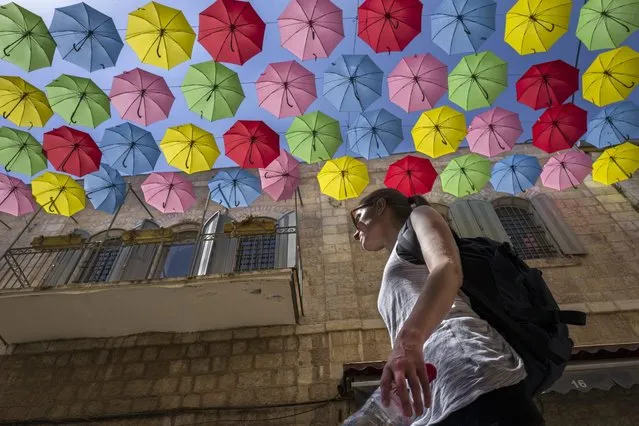 A woman walks down a popular pedestrian street in central Jerusalem, Israel, 13 September 2016, under a canopy of colorful umbrellas, an installation providing both shade and art during the hot summer months. (Photo by Jim Hollander/EPA)