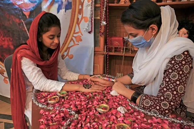 A beautician (R) applies Henna on the hands of a customer at a beauty salon ahead of the Muslim festival of Eid al-Adha in Rawalpindi on July 30, 2020. Eid al-Adha, feast of the sacrifice, marks the end of the Hajj pilgrimage to Mecca and commemorates Prophet Abraham's readiness to sacrifice his son to show obedience to Allah. (Photo by Aamir Qureshi/AFP Photo)