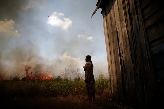 Miraceli de Oliveira reacts as the fire approaches their house in an area of the Amazon rainforest, near Porto Velho, Rondonia State, Brazil on August 16, 2020. (Photo by Ueslei Marcelino/Reuters)