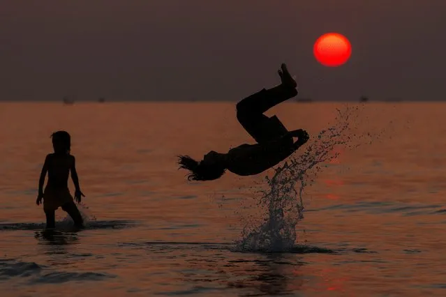 Palestinian children play in the waters of the Mediterranean sea off the coast of Gaza City, at sunset on December 30, 2022. (Photo by Mahmud Hams/AFP Photo)