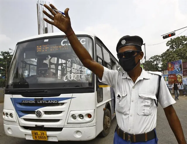 A traffic policeman uses a face mask as he controls the traffic movement on a busy road in Kolkata, India, October 2, 2015. (Photo by Rupak De Chowdhuri/Reuters)