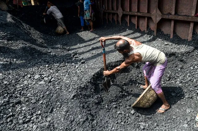 A labourer shifts coal in a basket to unload it from a cargo ship in Dhaka on August 13, 2020. (Photo by Munir Uz Zaman/AFP Photo)