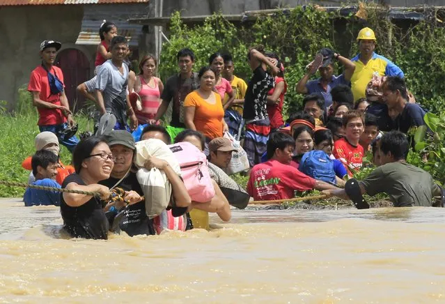 Residents hold on a rope while crossing flood waters brought by typhoon Koppu that battered Candaba town, Pampanga province, north of Manila October 20, 2015. (Photo by Romeo Ranoco/Reuters)