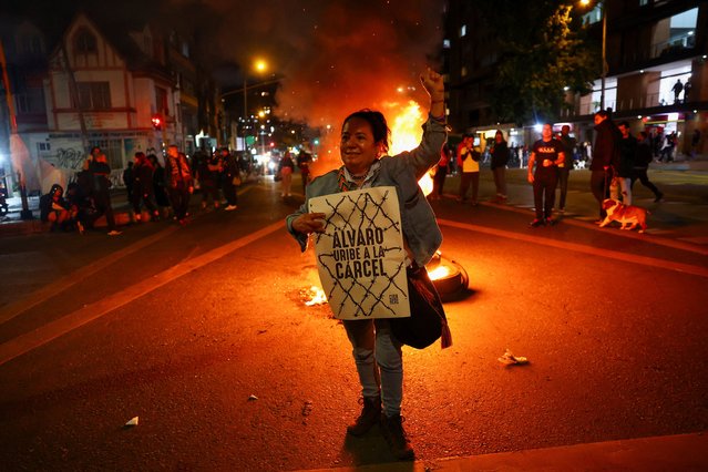 A woman holds a poster that reads “Alvaro Uribe goes to prison”, as people gather in celebration after a judge found former Colombian President Alvaro Uribe guilty of abuse of process and bribery of a public official, in Bogota, Colombia on July 29, 2025. (Photo by Luisa Gonzalez/Reuters)