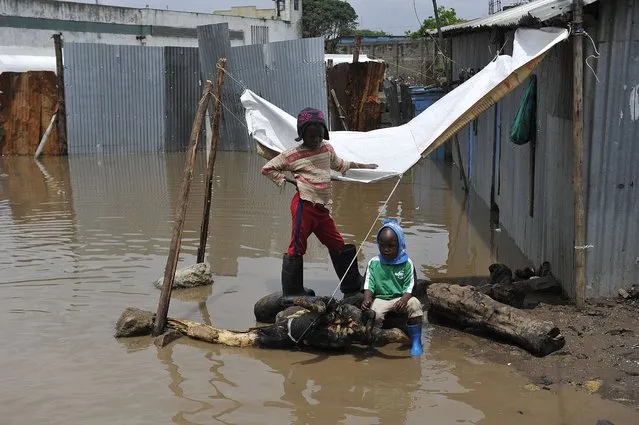 Two boys sit outside their flooded house at the Mukuru Kwa Njenga slum following heavy rainfall October 29, 2015, in the capital Nairobi. According to the weather forecast, the El Nino weather phenomenon is expected to hit Kenya, but says it is unlikely to unleash the fury and destruction of 1997. (Photo by Simon Maina/AFP Photo)