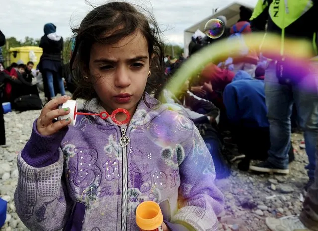 A migrant child blows soap bubbles at a transit camp in Gevgelija, Macedonia, after entering the country by crossing the border with Greece, September 29, 2015. (Photo by OgnenTeofilovski/Reuters)