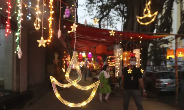 People walk past decorative lights on sale ahead of Diwali, the Hindu festival of lights, in Mumbai, India, Saturday, November 7, 2020. Diwali will be celebrated on Nov. 14. (Photo by Rafiq Maqbool/AP Photo)