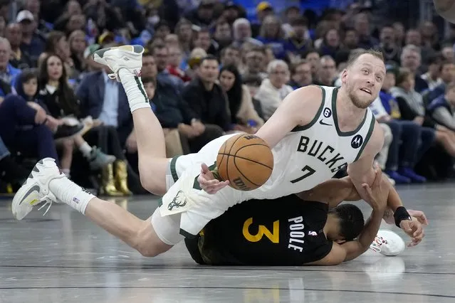 Milwaukee Bucks guard Joe Ingles (7) passes the ball over Golden State Warriors guard Jordan Poole (3) during the first half of an NBA basketball game in San Francisco, Saturday, March 11, 2023. (Photo by Jeff Chiu/AP Photo)