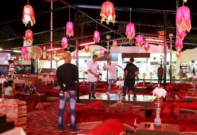 Tourists sit in a cafe as employees dance, in a main street full of cafes at the Red Sea resort of Sharm el-Sheikh, November 6, 2015. (Photo by Asmaa Waguih/Reuters)