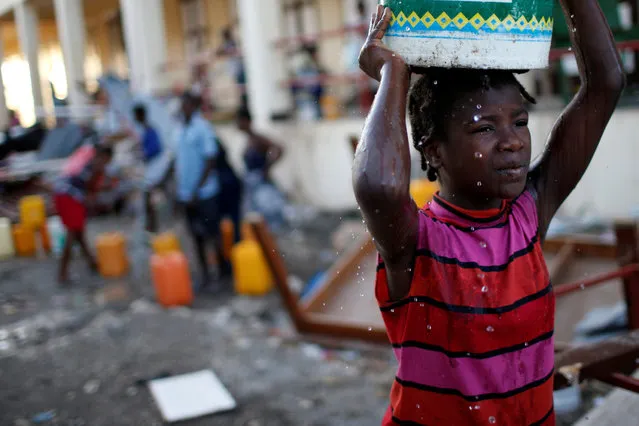 A girl carries a plastic container filled with water in a partially destroyed school used as a shelter after Hurricane Matthew hit Jeremie, Haiti, October 12, 2016. (Photo by Carlos Garcia Rawlins/Reuters)