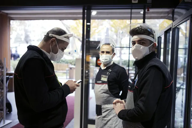 Workers wearing masks to help protect against the spread of coronavirus, stand at the entrance of a food market, in Ankara, Turkey, Friday, November 20, 2020. Turkey's daily coronavirus deaths hit a record high as a series of restrictions aiming to slow the surge of COVID-19 infections came into effect. The Health Ministry reported 141 deaths on Friday – the highest number of fatalities in one day for Turkey since the start of pandemic. (Photo by Burhan Ozbilici/AP Photo)