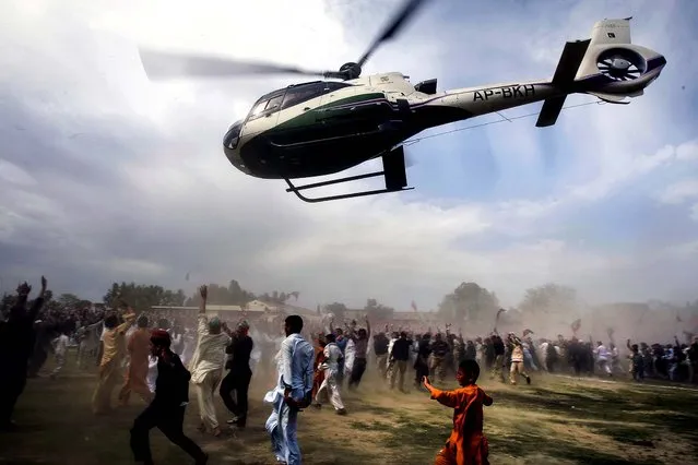 Supporters of Pakistan's former cricket star-turned-politician Imran Khan run for cover as a helicopter carrying their leader leaves after his election campaign rally in Charsadda, on May 4, 2013. Pakistan is scheduled to hold parliamentary elections on May 11, the first transition between democratically elected governments in a country that has experienced three military coups and constant political instability since its creation in 1947. (Photo by Mohammad Sajjad/Associated Press)