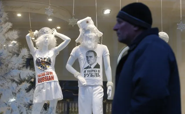 People walk past mannequins behind a window, with a T-shirt displaying a portrait of Russian President Vladimir Putin, in Moscow, December 22, 2014. The Russian rouble has extended its daily against the U.S. dollar on Monday thanks to foreign currency sales by exporters ahead of tax payments. The T-shirt reads, “In Rouble I trust”. (Photo by Sergei Karpukhin/Reuters)