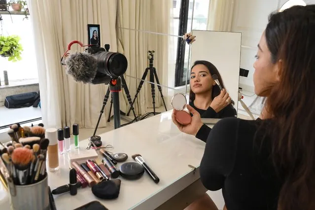 In this photo taken on March 16, 2023, social media beauty and lifestyle influencer Debasree Banerjee does her make-up while going live on her YouTube channel in Mumbai. Under the glow of a ring light in the spare bedroom of Mumbai high-rise, Indian make-up maven Debasree Banerjee has found fans across the world with a simple mantra: brown is beautiful. (Photo by Sujit Jaiswal/AFP Photo)
