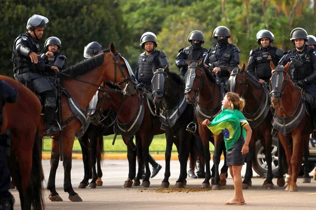 A demonstrator reacts next to members of security forces as supporters of Brazil's former President Jair Bolsonaro leave a camp outside the Army Headquarters, in Brasilia, Brazil on January 9, 2023. (Photo by Amanda Perobelli/Reuters)
