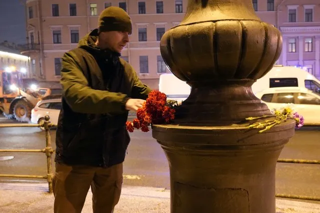A man lays flowers near the site of an explosion at a cafe in St. Petersburg, Russia, Sunday, April 2, 2023. An explosion tore through a cafe in the Russian city of St. Petersburg on Sunday, and preliminary reports suggested a prominent military blogger was killed and more than a dozen people were injured. (Photo by AP Photo/Stringer)