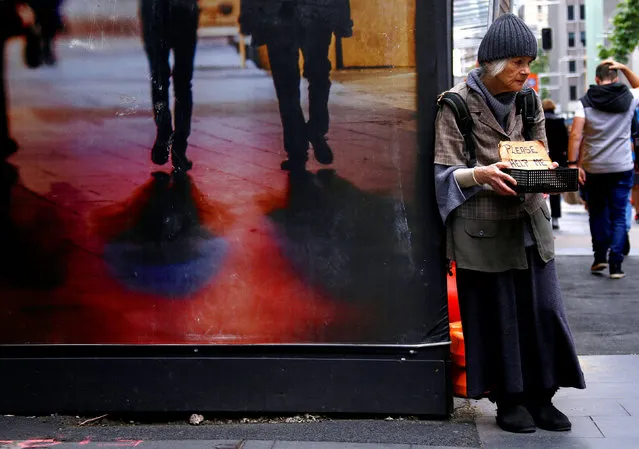 A woman claiming to be homeless holds a container bearing a sign reading “Please Help Me” as she begs for money on a footpath in central Sydney, Australia, October 28, 2016. (Photo by David Gray/Reuters)