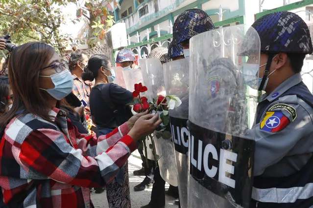 Supporters give roses to police while four arrested activists make a court appearance in Mandalay, Myanmar, Friday, February 5, 2021. Hundreds of students and teachers have taken to Myanmar's streets to demand the military hand power back to elected politicians, as resistance to a coup swelled with demonstrations in several parts of the country. (Photo by AP Photo/Stringer)