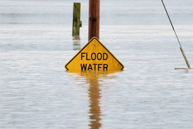 A sign warning drivers about flood water is partially covered by water in an area flooded by the Snohomish River, as an atmospheric river brings rain and flooding to the Pacific Northwest, in Snohomish, Washington, U.S., December 11, 2025. (Photo by David Ryder/Reuters)