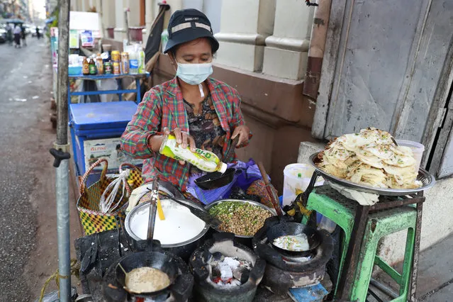 A woman prepares snacks to sell them to customers at her roadside shop Wednesday, February 3, 2021, in Yangon, Myanmar. (Photo by Thein Zaw/AP Photo)