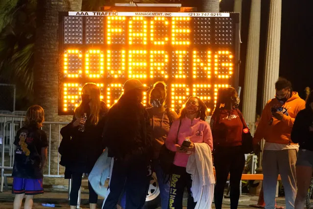 A sign encourages visitors to wear face masks amid the COVID-19 pandemic Friday, February 19, 2021, in Santa Monica, Calif. (Photo by Marcio Jose Sanchez/AP Photo)