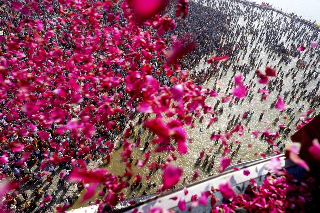 Government officials shower flower petals from a helicopter on to pilgrims gathered at the Sangam, the confluence of three rivers, the Ganges, the Yamuna and the mythical Saraswati, on Maghi Purnima or the full-moon day during the Maha Kumbh festival in Prayagraj, India  Wednesday, February 12, 2025. (Photo by Rajesh Kumar Singh/AP Photo)