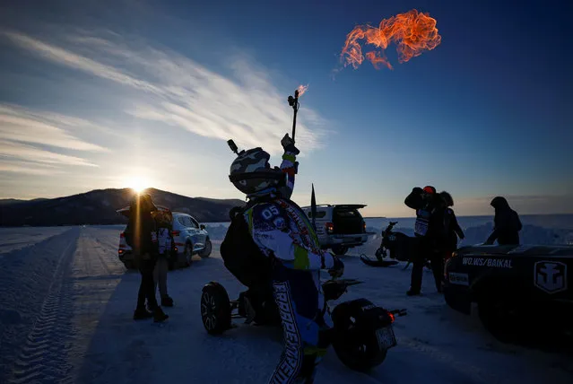 A participant lights a torch during Baikal Mile 2021 festival of speed on the ice of frozen Lake Baikal near the village of Maksimikha in the Republic of Buryatia, Russia on March 6, 2021. (Photo by Maxim Shemetov/Reuters)