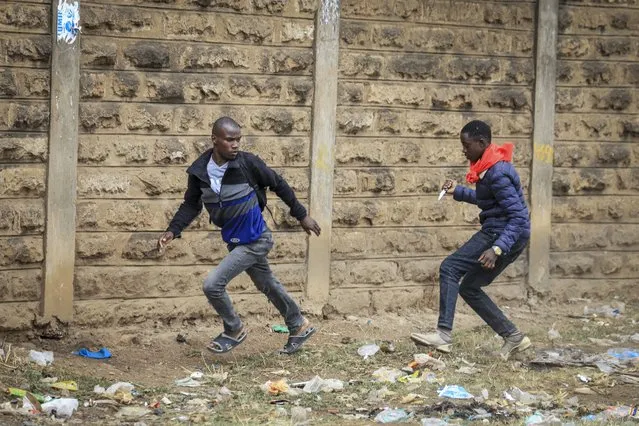 An unidentified man holding a knife, right, tries to rob a pedestrian, left, during clashes between police and protesters in the Mathare neighborhood of Nairobi, Kenya Wednesday, July 12, 2023. (Photo by AP Photo/Stringer)
