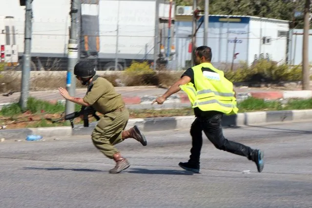 A Palestinian (R) posing as a journalist runs after a wounded Israeli soldier to continue stabbing him before being shot dead near the West Bank city of Hebron October 16, 2015. (Photo by Bilal al-Taweel/Reuters)