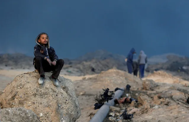 A boy sits on a rock in front of oilfields burned by Islamic State fighters in Qayyara, south of Mosul, Iraq November 23, 2016. (Photo by Goran Tomasevic/Reuters)