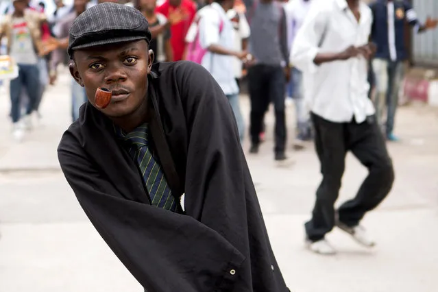 A sapeur, member of the “La Sape” movement poses for a photograph as he pays homage at the grave of their founder Stervos Niarcos Ngashie during the 20th anniversary of his death, at the Gombe cemetery in Kinshasa, Democratic Republic of Congo, February 10, 2015. The “La Sape” movement, known as “Societe des Ambianceurs et des Personnes Elegantes” started in the Congo in the 1960s and encourages dressing flamboyantly. (Photo by Rey Byhre/Reuters)