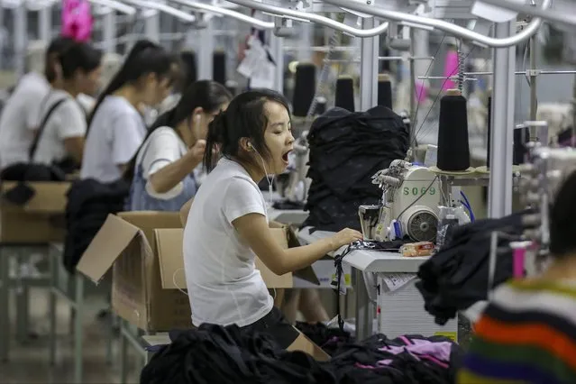 In this Thursday, August 2, 2018, photo, a woman yawns at a factory making swimming suits in Jinjiang city in southeast China's Fujian province. China's exports accelerated in July, showing little impact from a U.S. tariff hike, while sales to the United States rose 13.3 percent over a year earlier. (Photo by Chinatopix via AP Photo)