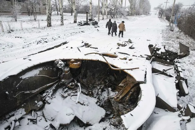 Locals walk past a destroyed Ukrainian army armoured personnel carrier in the town of Vuhlehirsk, about 10 km (6 miles) to the west of Debaltseve, February 16, 2015. (Photo by Baz Ratner/Reuters)