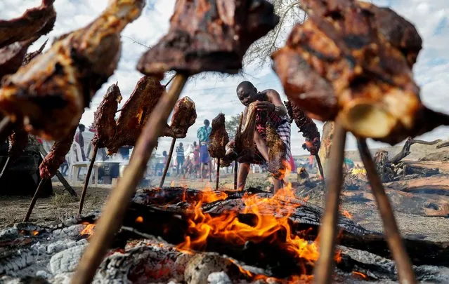 David Pariken 46, of the indigenous Maasai community, roasts meat at the inaugural Maa Cultural Week dubbed The Maa-Festival aimed to promote peace, tourism, and cultural exchange as the wildebeests (Connochaetes taurinus) make their annual cross border migration at the Sekenani village, in the Maasai Mara National Reserve, in Narok County, Kenya on August 22, 2023. (Photo by Thomas Mukoya/Reuters)