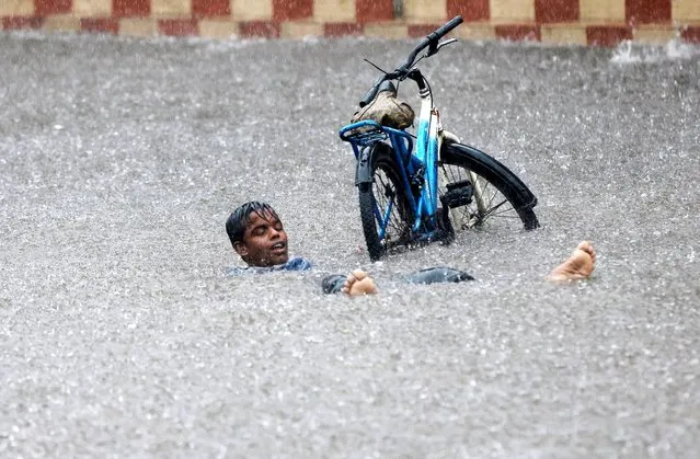 A boy plays on a flooded road amid heavy rainfall in Ahmedabad, India on September 17, 2023. (Photo by Amit Dave/Reuters)