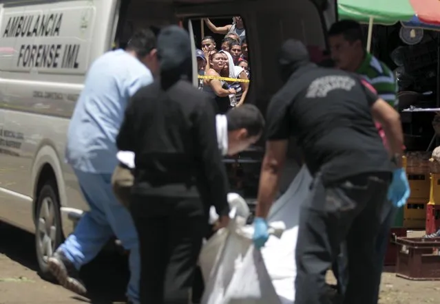Family members react as forensic technicians and police officers remove the dead body of Miguel Angel Acevedo at a crime scene at La Tiendona market in San Salvador, July 2, 2015. Acevedo was killed by suspected gang members as he was selling potatoes at La Tiendona market, according to local media. (Photo by Jose Cabezas/Reuters)