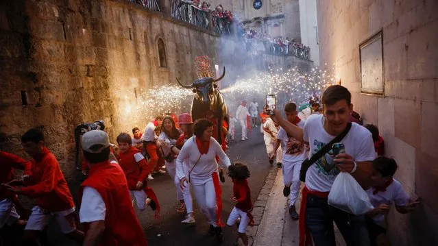 Revellers run next to the Fire Bull, a man carrying a bull figure packed with fireworks, during the San Fermin festival in Pamplona, Spain on, July 6, 2022. (Photo by Juan Medina/Reuters)