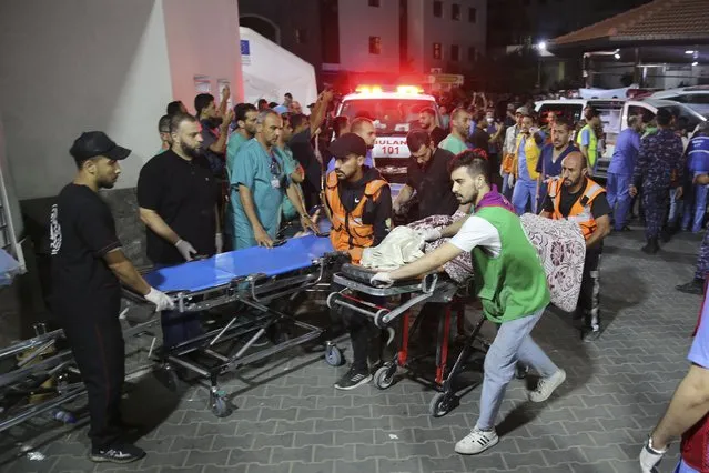 Palestinian medics wheel a person killed in Israeli strikes to the morgue of Shifa Hospital in Gaza City, Friday, October 13, 2023. (Photo by Ali Mahmoud/AP Photo)