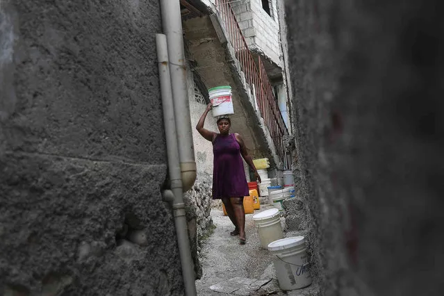 A woman carries a bucket with water she purchased from a neighbor for the equivalent of twenty cents of a dollar at the Bourdon quarter of Port-au-Prince, Haiti, Monday, July 12, 2021. Haiti has one of the lowest rates of access to clean water and sanitation infrastructure in the western hemisphere. (Photo by Matias Delacroix/AP Photo)