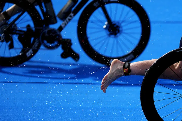 Water comes off the foot of Jessica Learmonth, of Britain, as she transitions in the rain from the bike to the running leg during the women's individual triathlon at the 2020 Summer Olympics, Tuesday, July 27, 2021, in Tokyo. (Photo by David Goldman/AP Photo)